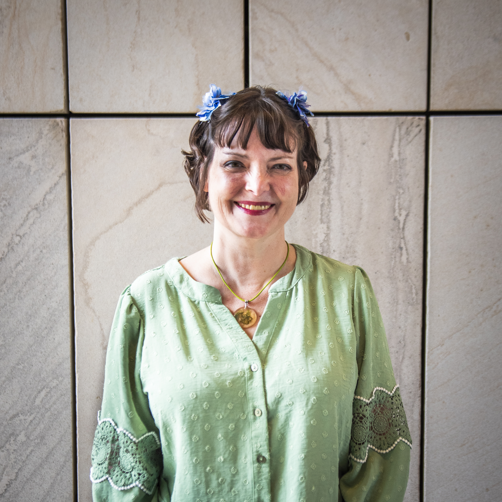 Person wearing green in front of a stone wall