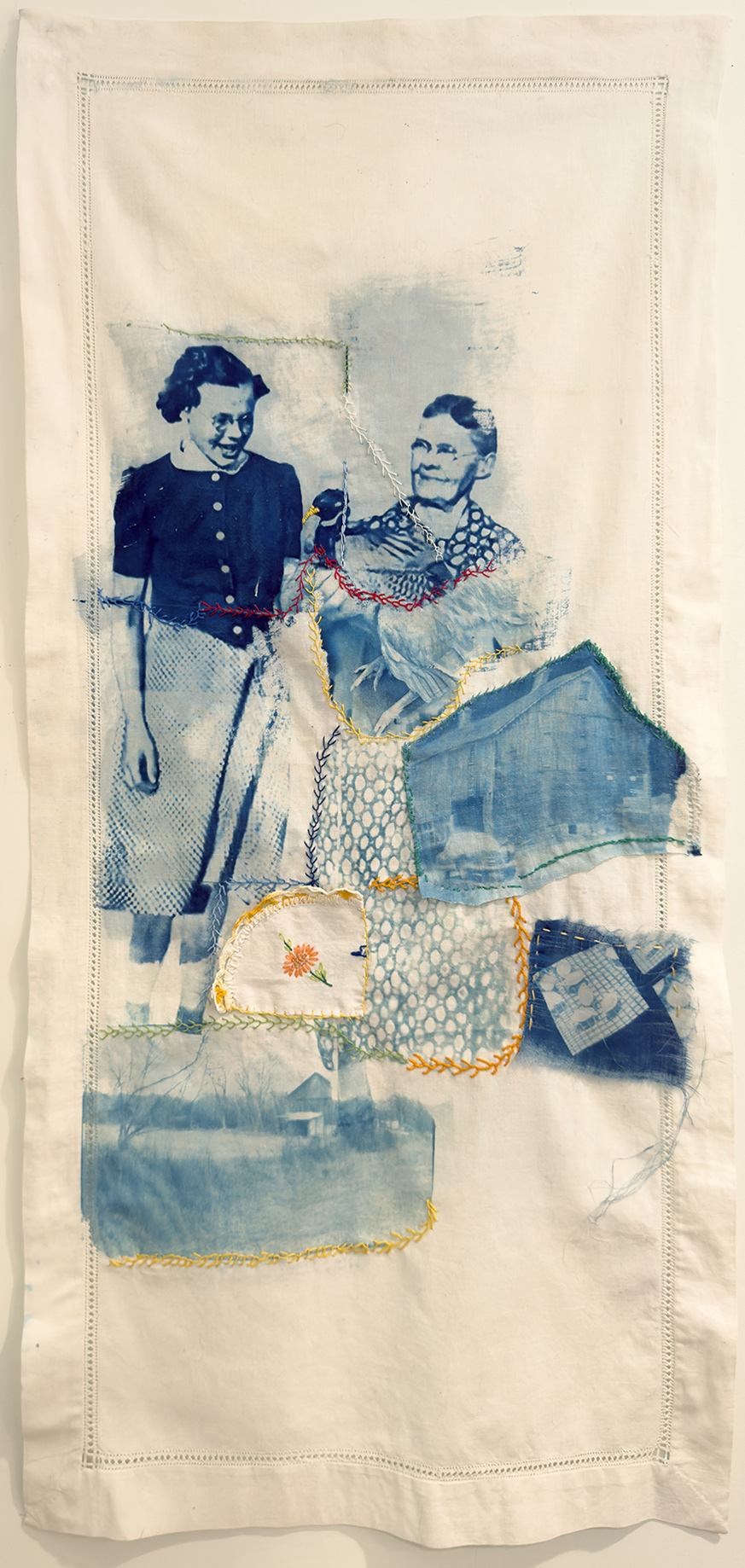 Cyanotype prints of a little girl and elderly woman, both with glasses, stitched with other patchwork indigo fabric on a long white banner