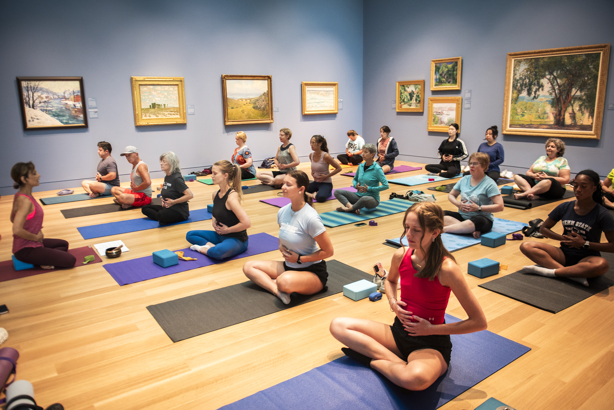 A large group of people doing yoga in an art museum