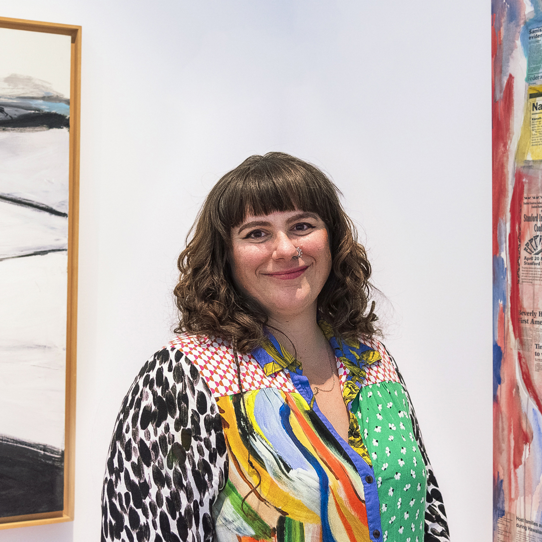Woman in a colorful blouse with wavy brown hair in an art gallery