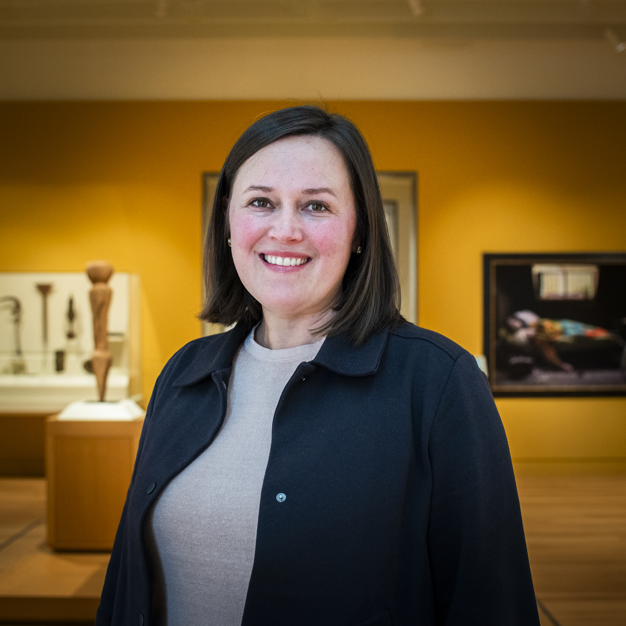 Woman in front of a yellow gallery wall