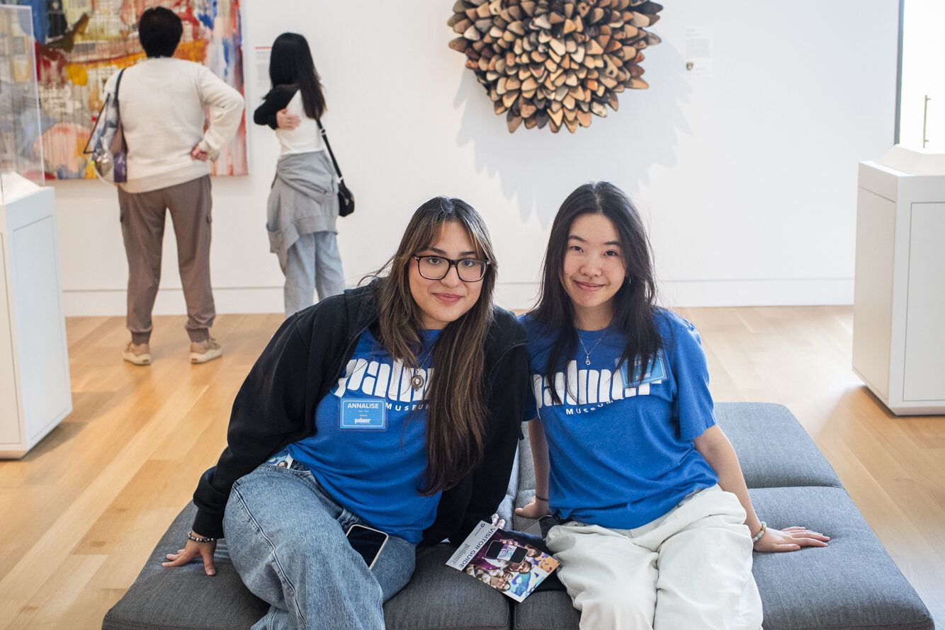 Two women sitting on a gallery bench