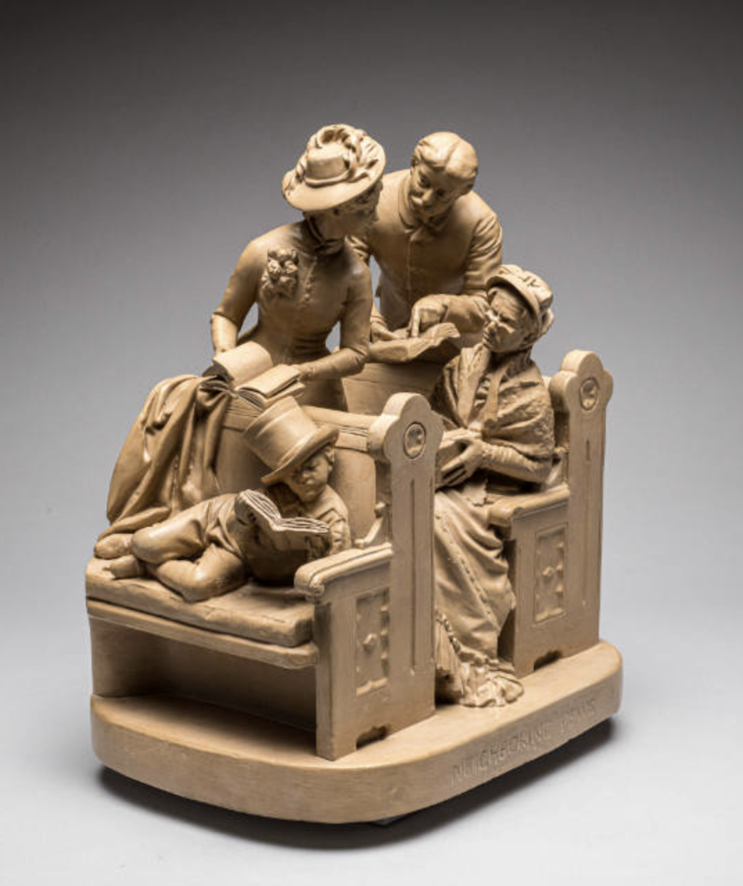 Sculpture in beige painted plaster of a church scene with a group of people in fancy 19th-century church clothes whispering in pews. An elderly woman frowns disapprovingly and a child with a top hat slid to one side lays reading a book in the front pew.
